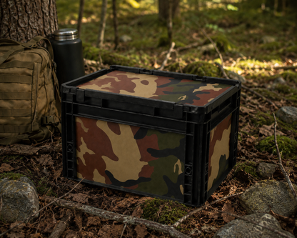 OctoVan Eurobox Camouflage Tarn im Outdoor-Einsatz im Wald mit Rucksack und Campingausrüstung – robuste Aufbewahrungsbox für Vanlife, Camping, Offroad und Abenteuer.